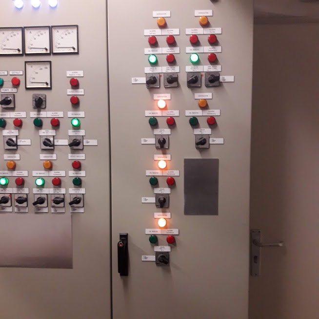 A commercial electrical control panel with illuminated green, amber and red indicator lamps, ammeters and labelled rotary switches, commissioned by Hi Elec-Tech Solutions.