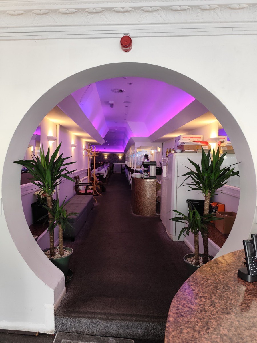 Colour-changing LED cove and feature lighting installed along a restaurant ceiling in East London, glowing purple and warm white, wired by Hi Elec-Tech Solutions.