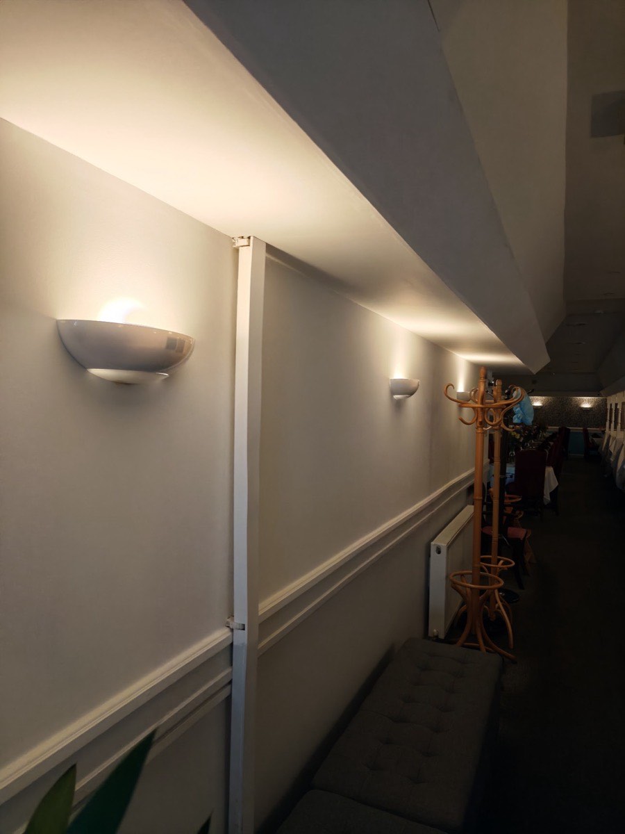 Warm wall uplighters installed along a restaurant dining room in East London, casting a soft glow up the walls, fitted by Hi Elec-Tech Solutions.